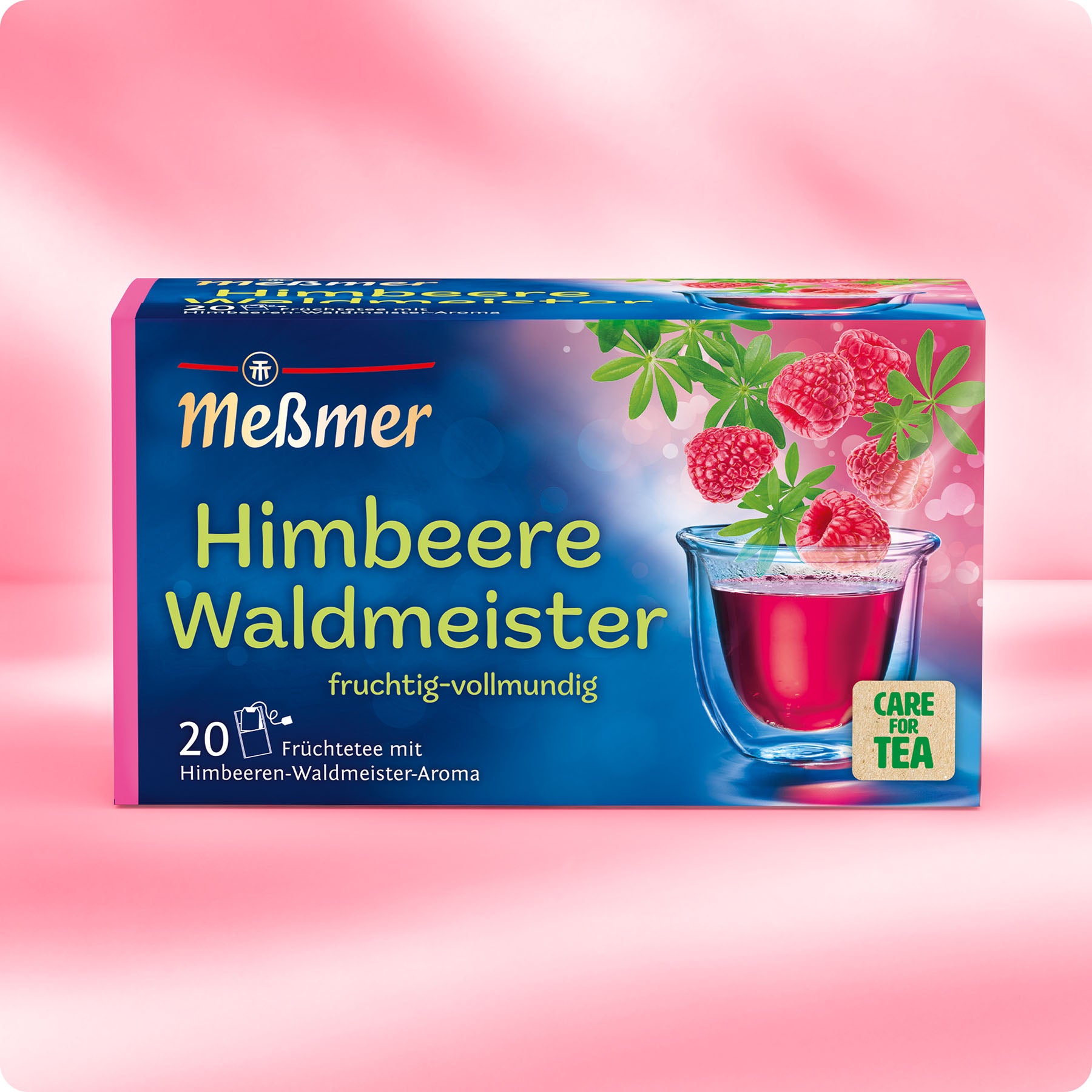 Meßmer Himbeere-Waldmeister Früchtetee mit fruchtigem Aroma, Verpackung mit Himbeeren und Waldmeisterblättern neben einer Tasse mit rotem Tee vor rosa Hintergrund