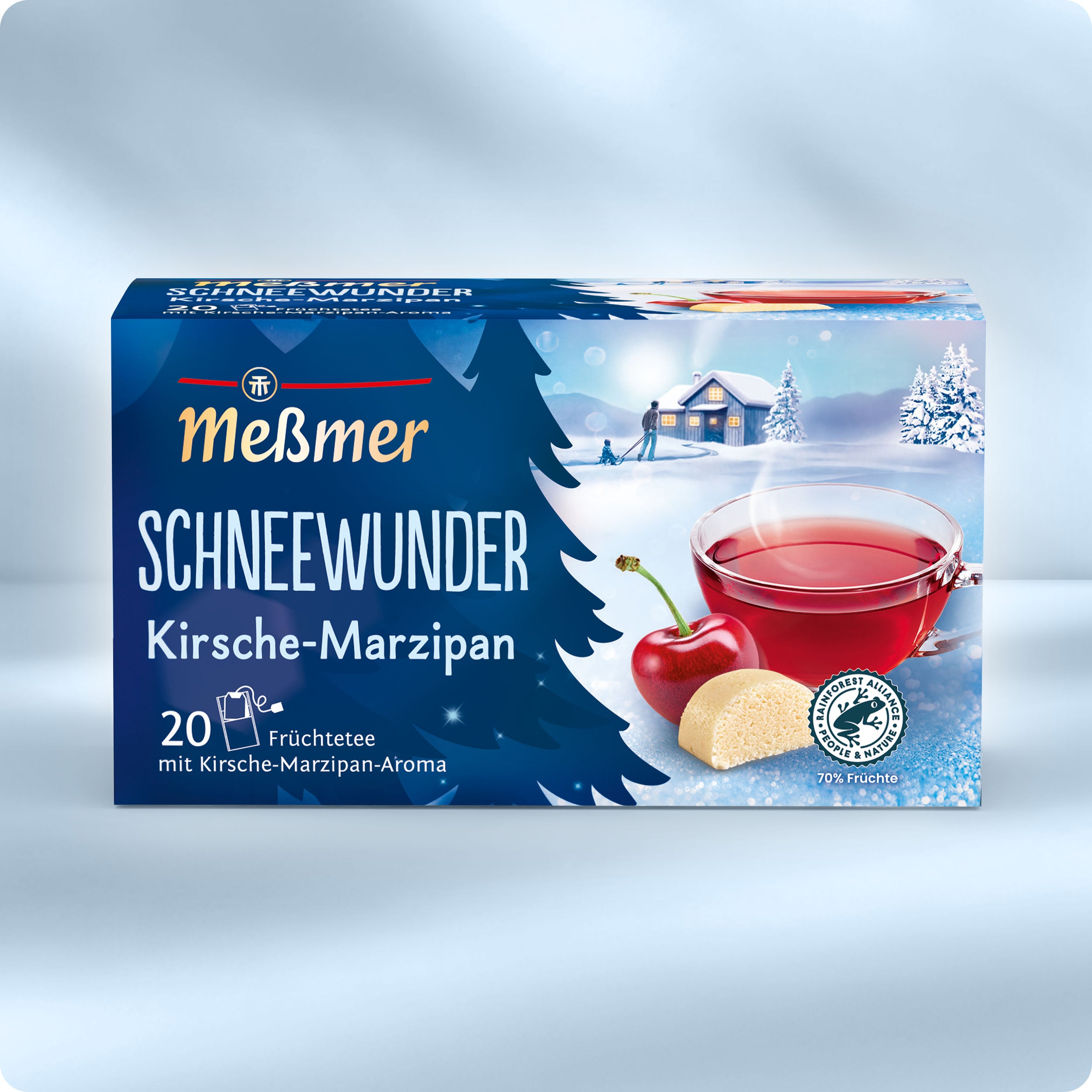 Eine Schachtel Meßmer Schneewunder Tee ist auf einem verschneiten Hintergrund mit einem Glas rotem Tee, Kirschen, Marzipanstücken und einer illustrierten verschneiten Hüttenszene im Hintergrund abgebildet.
