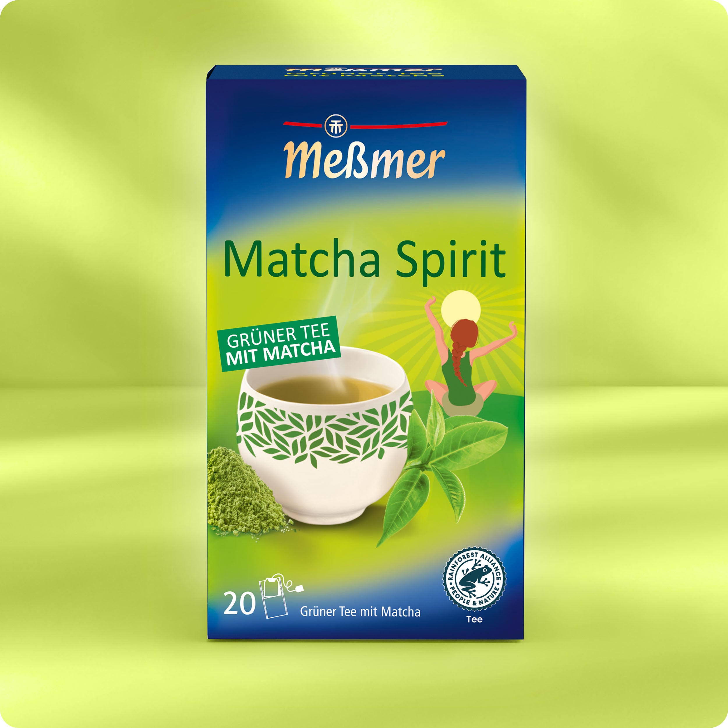 Eine Schachtel Meßmer DE Matcha Spirit Grüner Tee mit Matcha, mit einer weißen Tasse, grünen Blättern, Matcha-Pulver und der Abbildung einer sich reckenden Person im Hintergrund.