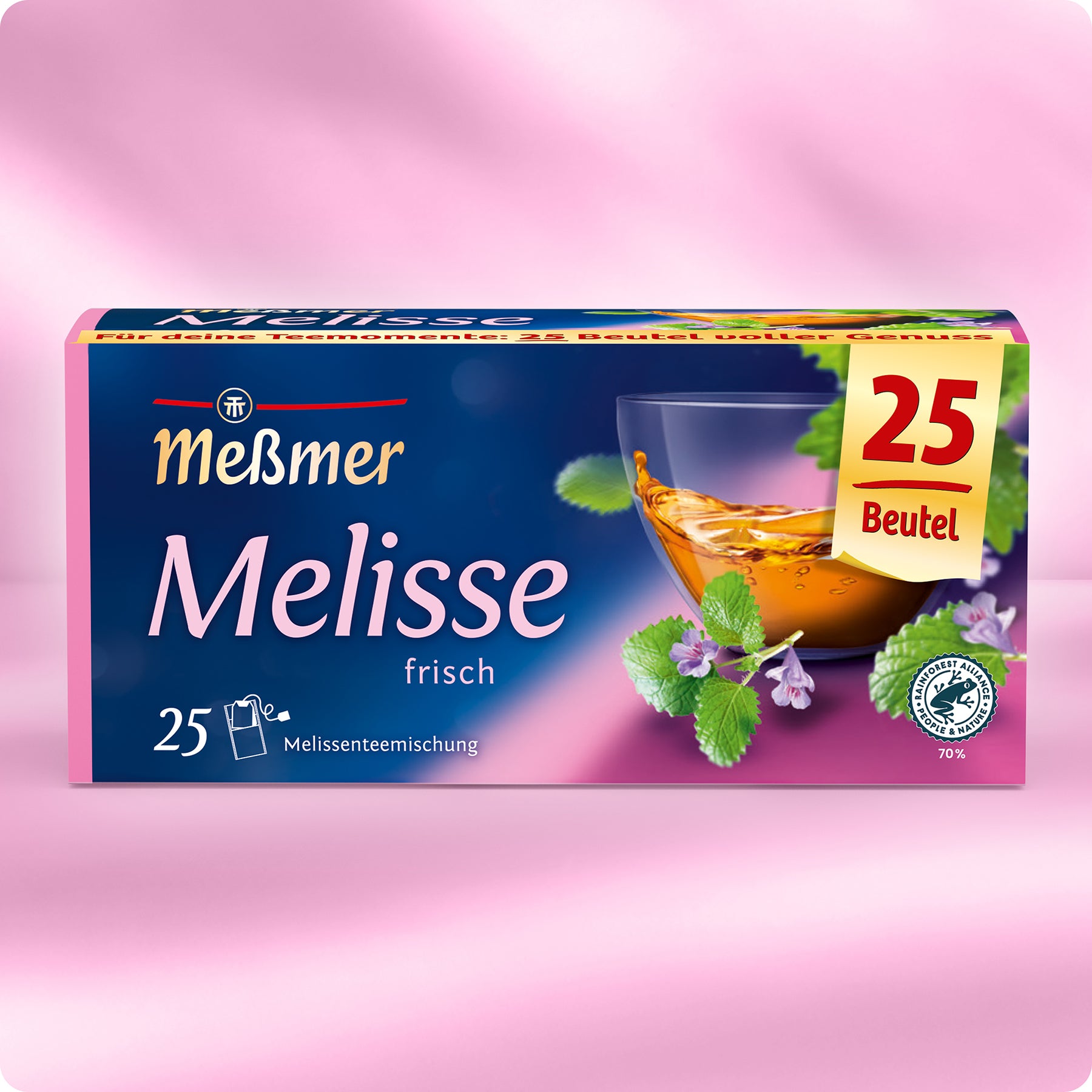 Eine Schachtel Meßmer DE Melisse-Tee (25 Beutel), abgebildet mit einer Glastasse mit Tee, frischen Melissenblättern und kleinen lila Blüten auf rosa Hintergrund.
