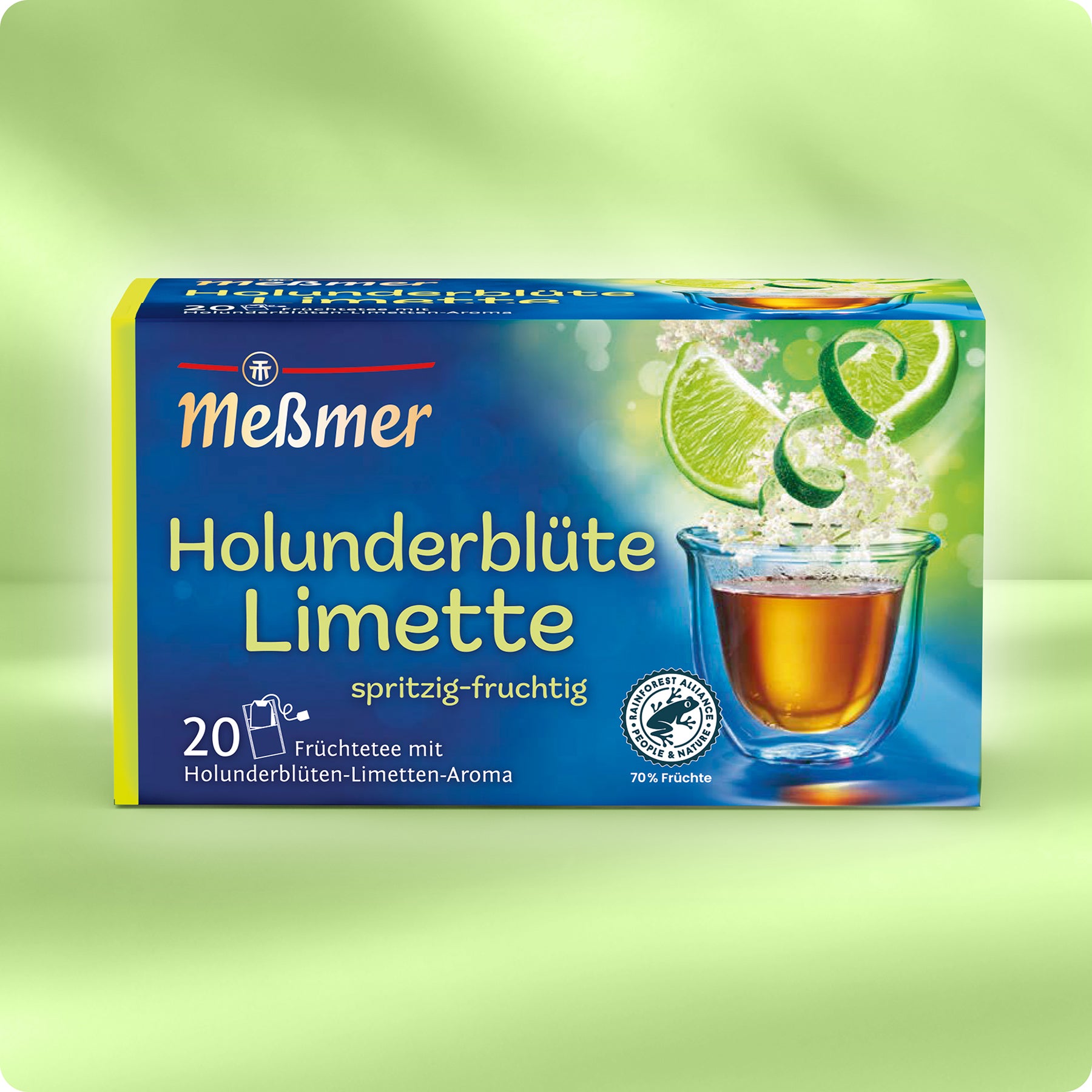 Meßmer DE Holunderblüte-Limette: Eine Schachtel mit 20 Früchteteebeuteln mit Holunderblüten-Limetten-Geschmack, die ein Glas Tee, Holunderblüten und Limettenscheiben auf einem grünen Hintergrund zeigen.