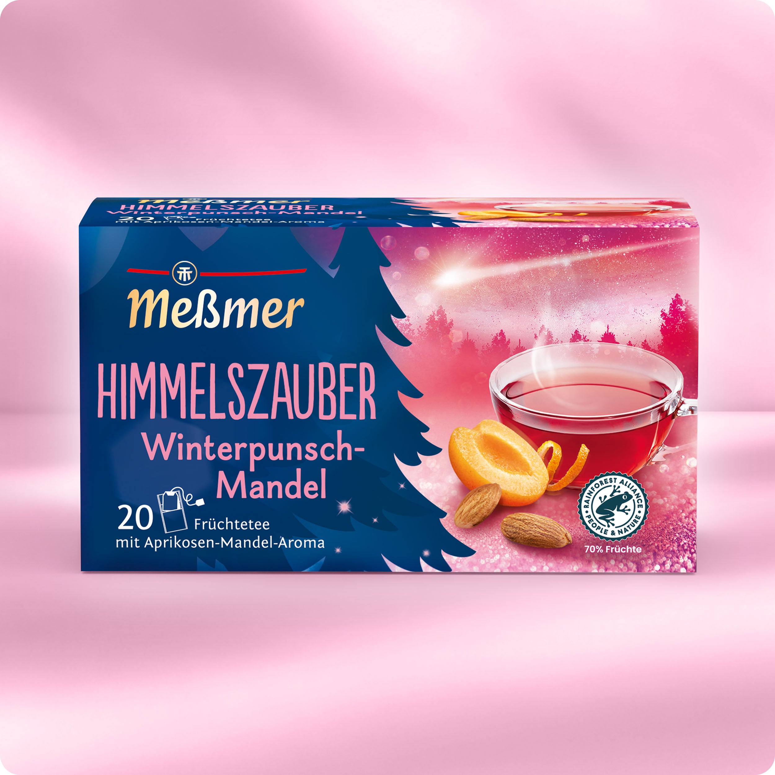 Eine Schachtel des Meßmer DE Wintertee-Bestseller-Sets wird mit einem Glas Tee, Aprikosenhälften und Mandeln auf einem rosafarbenen Hintergrund mit Wintermotiven präsentiert.