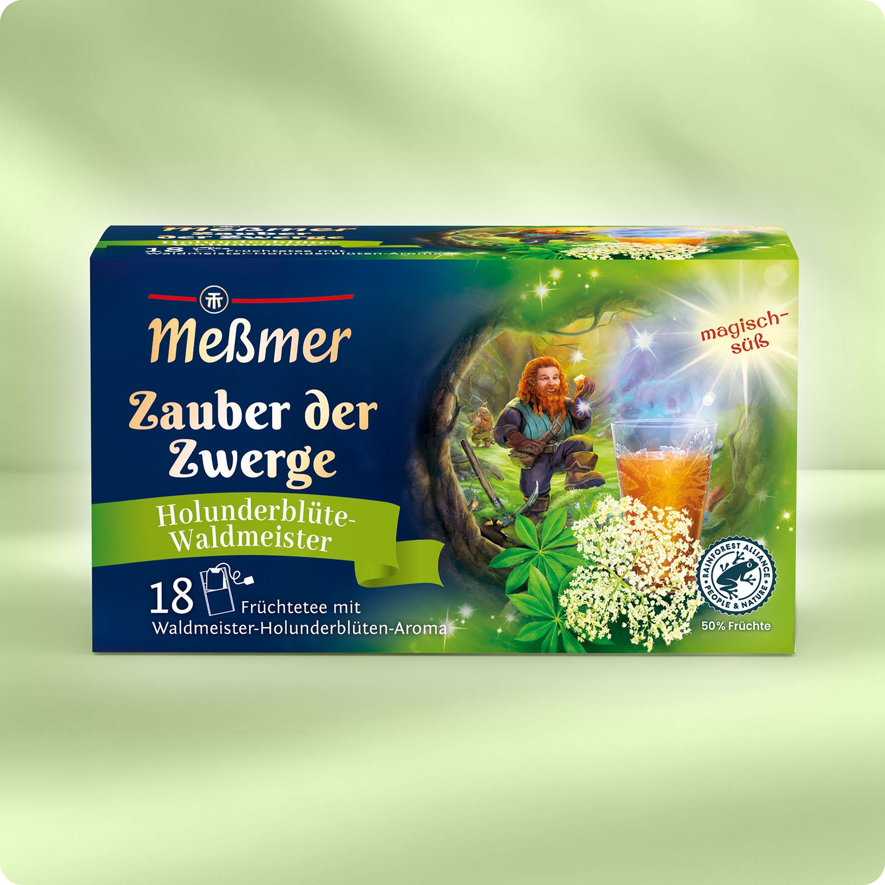Eine Schachtel Meßmer DE Zauber der Zwerge Tee mit Holunderblüten- und Waldmeistergeschmack ist mit einem Gnom, Holunderblüten, einem Glas Tee und leuchtend grünen und gelben Farben verpackt.