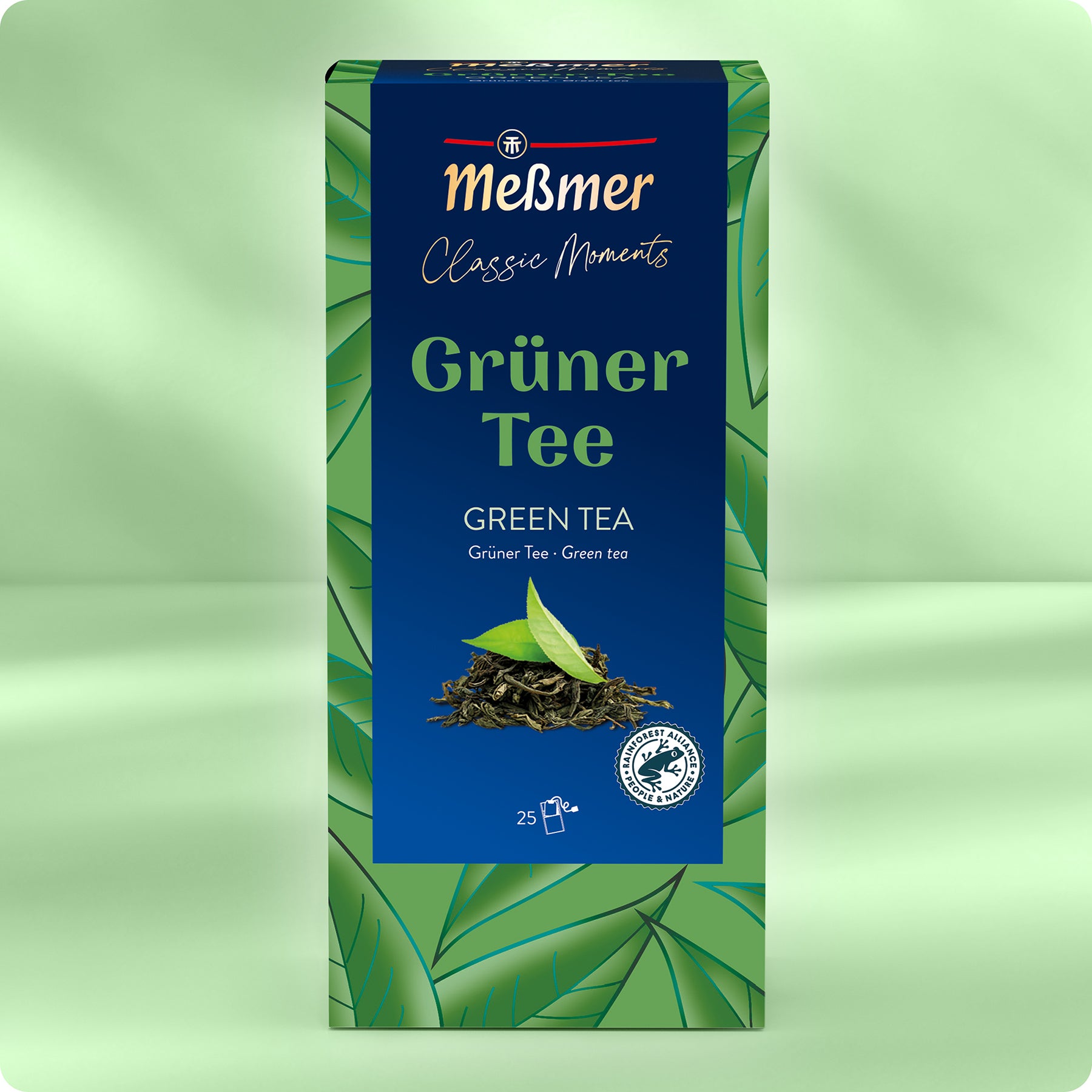 Eine Schachtel Meßmer DE Grüner Tee ist mit einem grünen und blauen Blattmuster, dem Text Grüner Tee" und Grüner Tee" versehen, von Asien inspiriert, enthält 25 Teebeutel und ist mit Logos für umweltfreundliche Zertifizierungen versehen.