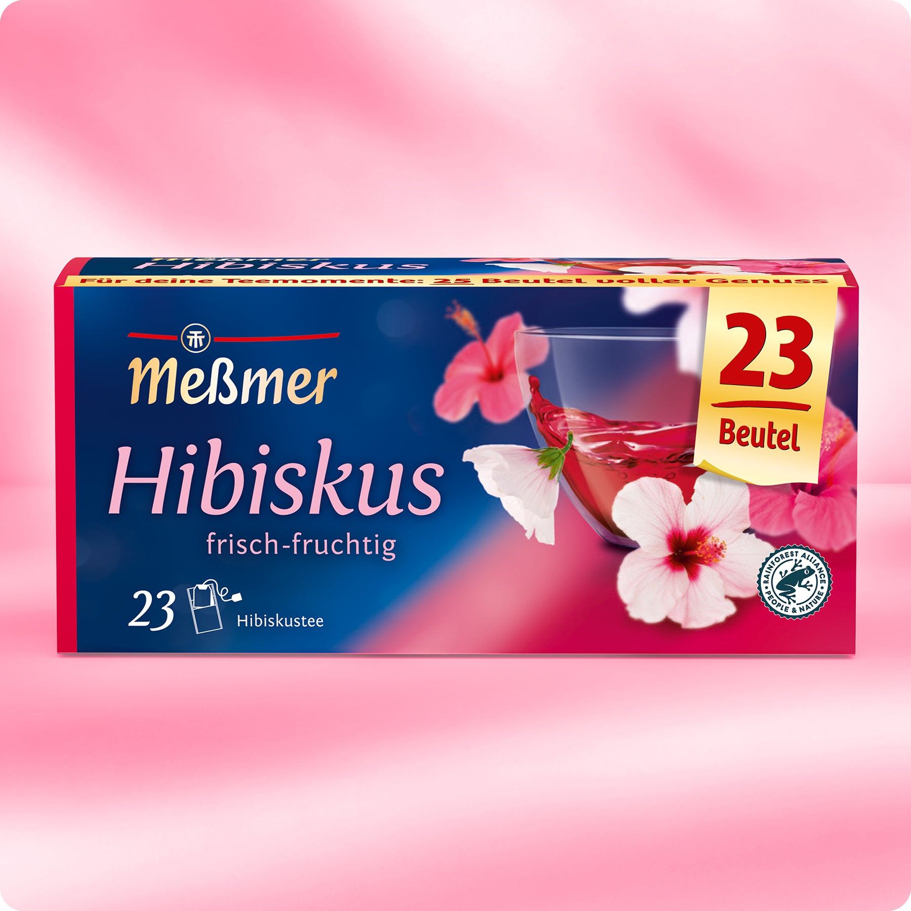 Eine Schachtel Meßmer DE Hibiskus-Tee mit 23 Beuteln zeigt Hibiskusblüten und ein Glas mit rotem Tee auf einem Hintergrund mit rosa Farbverlauf. Auf dem Etikett steht "frisch-fruchtig".