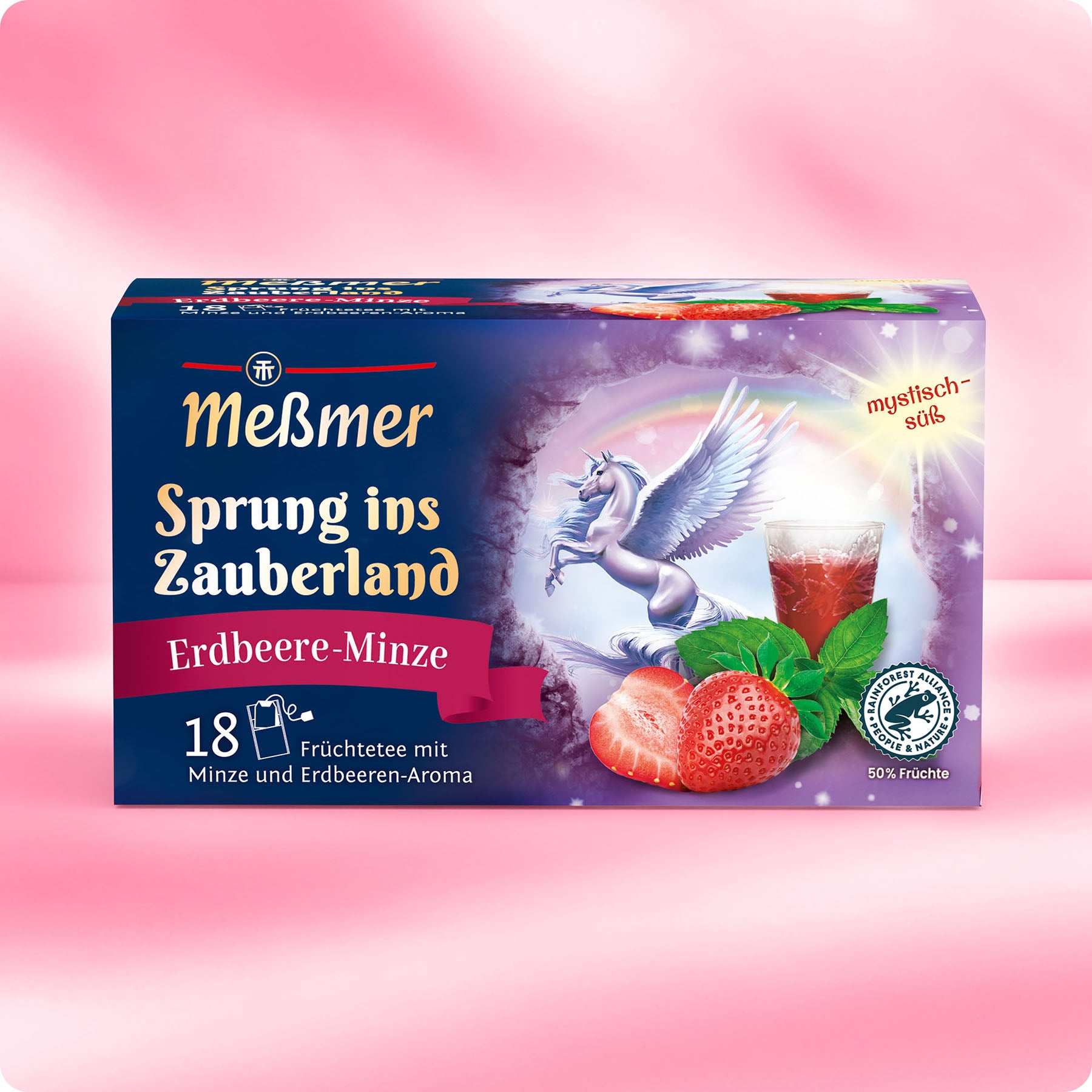 Eine Schachtel Meßmer DE "Sprung ins Zauberland" Tee mit 18 Beuteln mit fruchtigen Geschmacksrichtungen wie Erdbeere und Minze, einem geflügelten Einhorn, einem Glas Tee und einem rosa magischen Hintergrund auf der Verpackung.