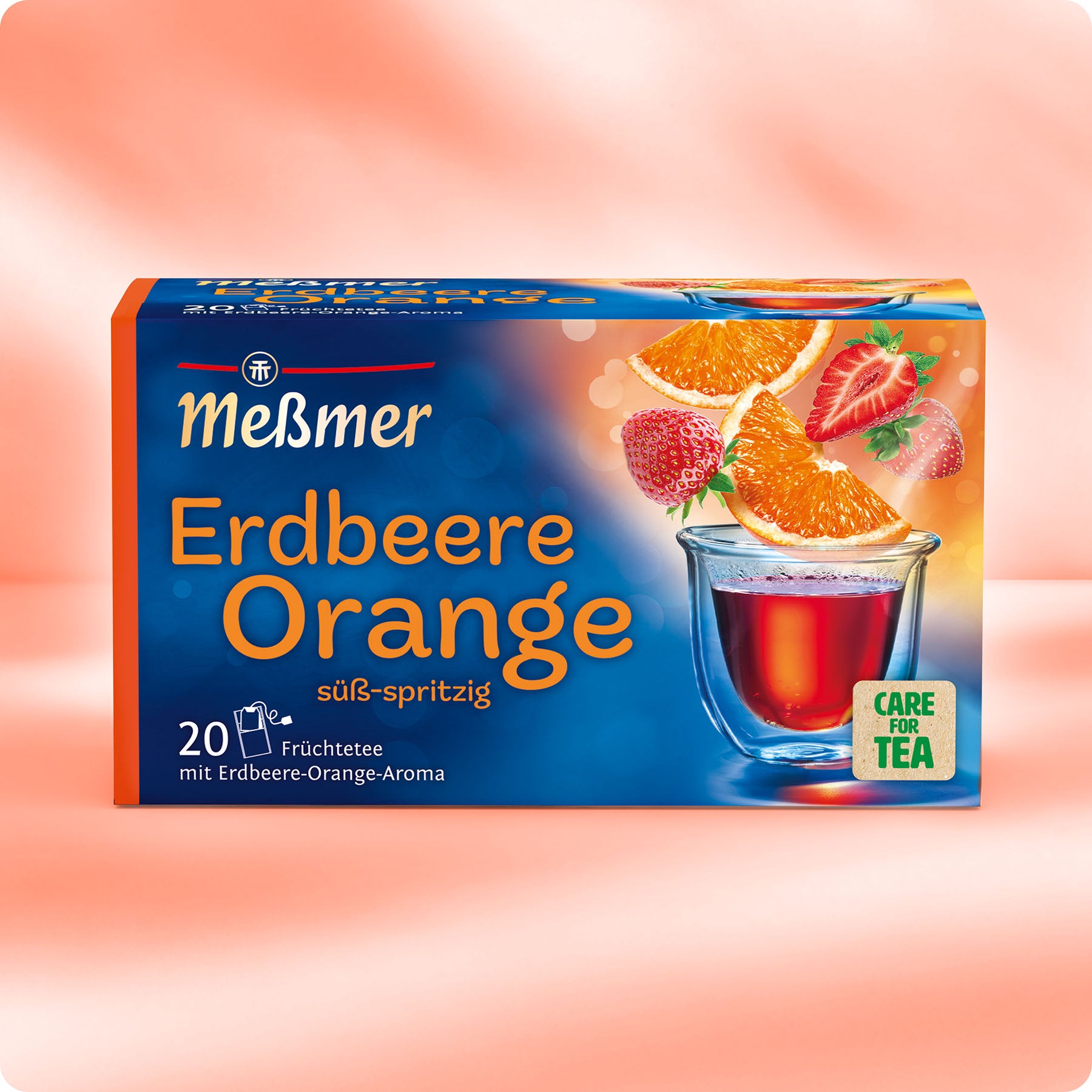 Verpackung des Früchtetees Erdbeere-Orange von Meßmer mit Erdbeeren, Orangenscheiben und aromatischem Tee in Glas vor orangefarbenem Hintergrund.