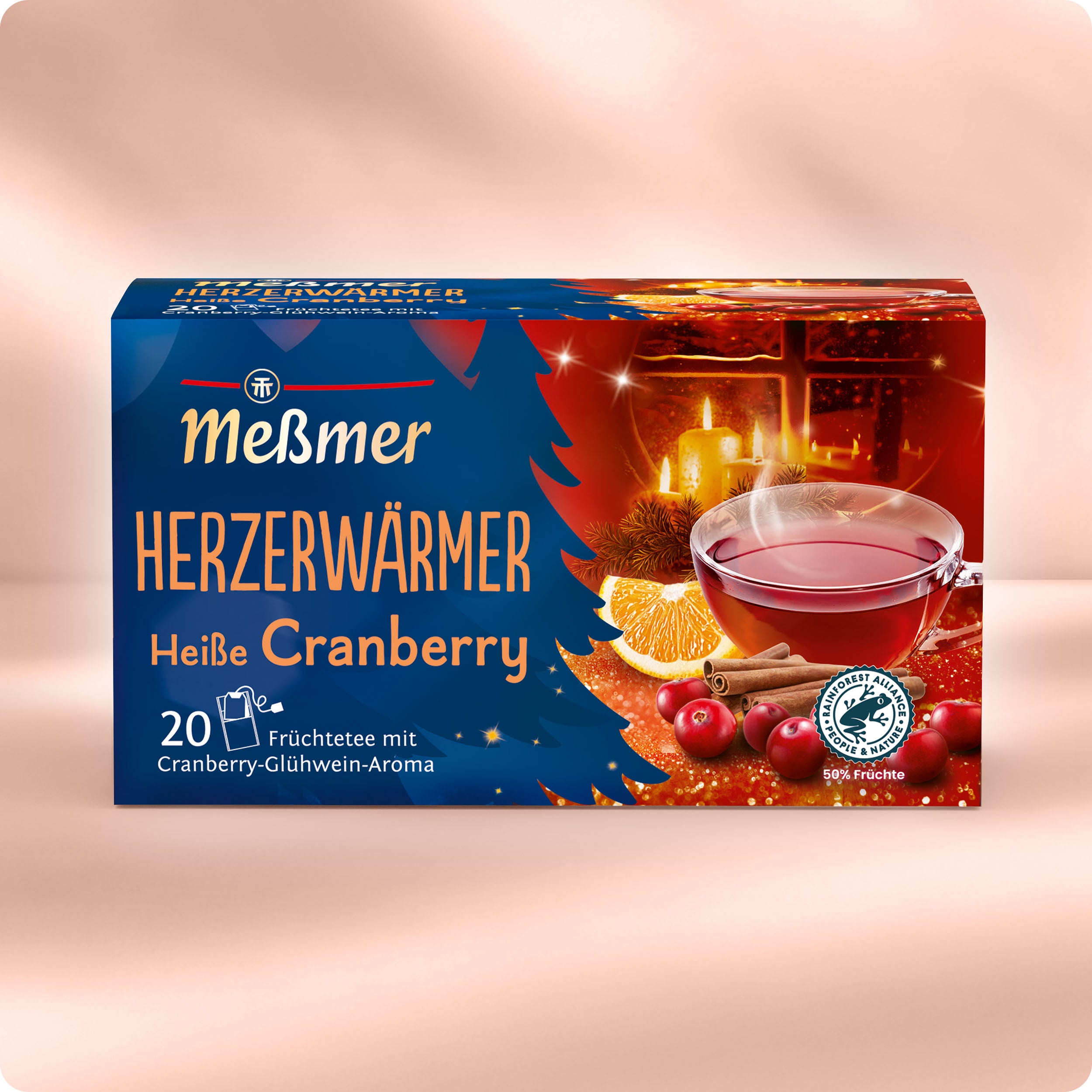 Eine festliche Schachtel Meßmer DE Herzerwärmer enthält 20 Früchteteebeutel mit Cranberry-Glühweingeschmack, verziert mit einer winterlichen Grafik aus rotem Tee, Cranberries, Orangenscheiben und leuchtenden Lichtern.