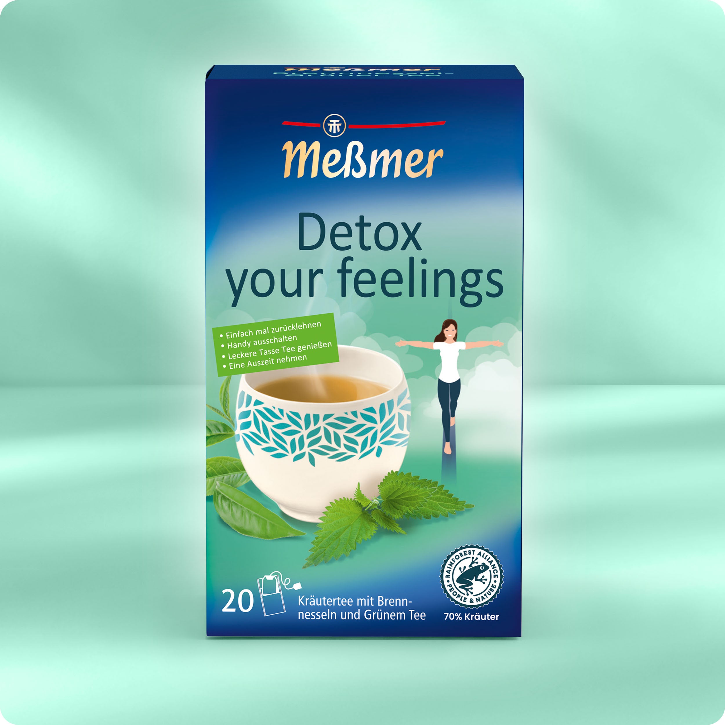Eine Schachtel Meßmer DE Detox your feelings Tee mit 20 Beuteln enthält Brennnessel und grünen Tee. Die Verpackung zeigt eine Tasse mit Kräutern, eine sich reckende Frau und einen grünen Hintergrund - perfekt für einen frischen Start in den Tag.